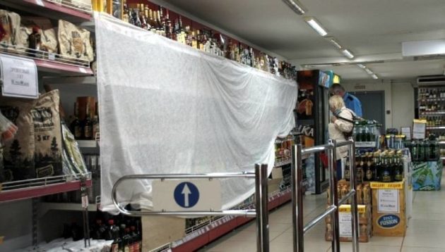 Regály s alkoholom sú po 23. hodine v obchodoch zahalené takýmito plachtami.